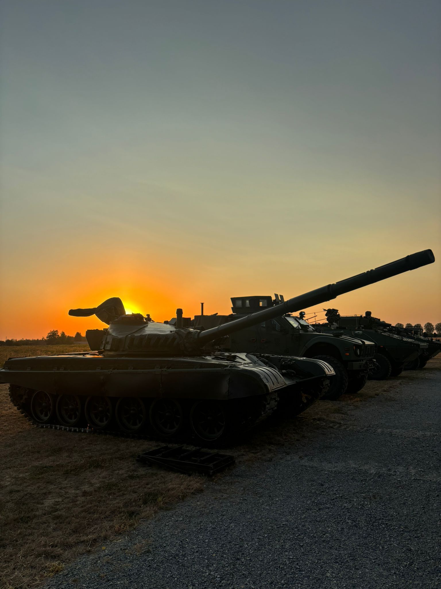Main battle tank and armored personnel carriers staged at sunset for the DEFCROS outdoor static display