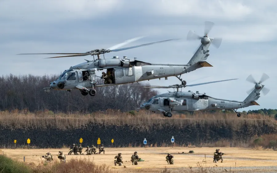 Two helicopters landing troops on an open training field