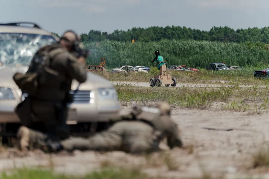 Operators firing from cover behind a vehicle on an outdoor range