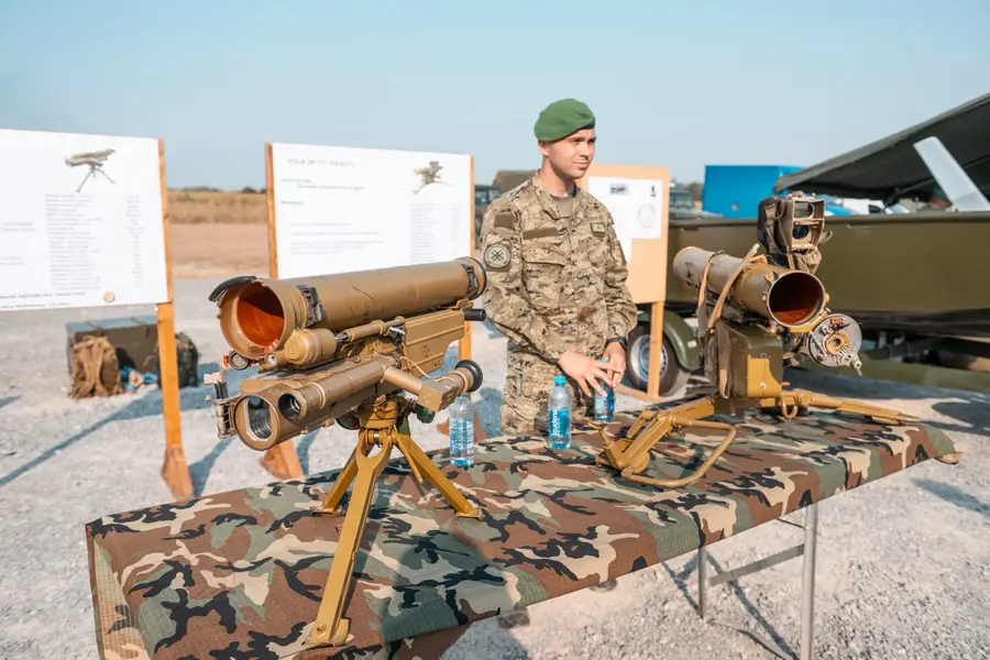 Soldier presenting anti-tank weapons on a camouflage-covered table outdoors