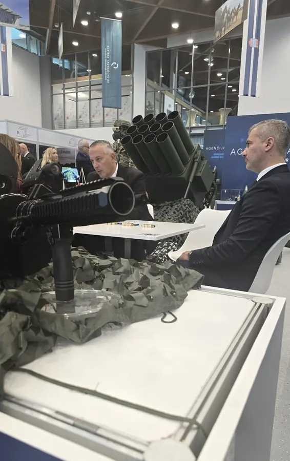 Exhibitor meeting alongside a multiple-launch rocket system on display