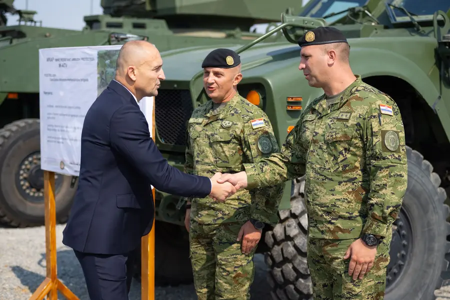 Officials shaking hands with Croatian Army soldiers in front of an armoured vehicle